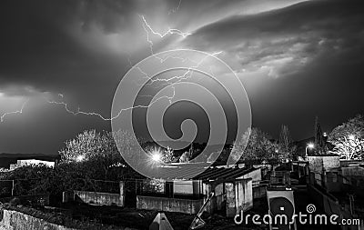 Lightning cracking during thunderstorm over houses of tiny town Stock Photo